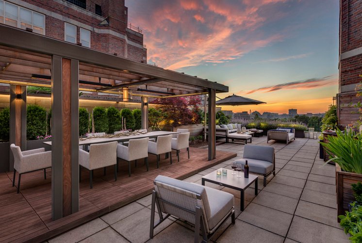 Rooftop terrace with dining pergola, lounge seating, and skyline views at sunset