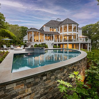 Curved above ground pool with spa and fire pit. Light up house in the background.
